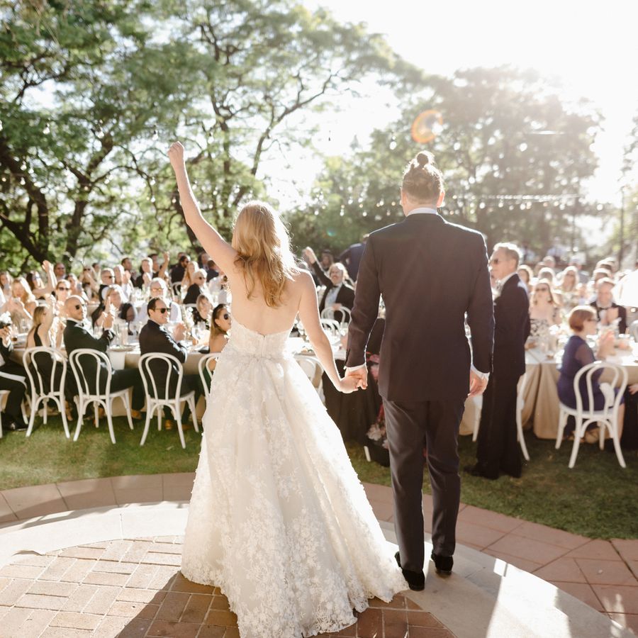bride and groom make wedding reception entrance in front of guests seated at tables