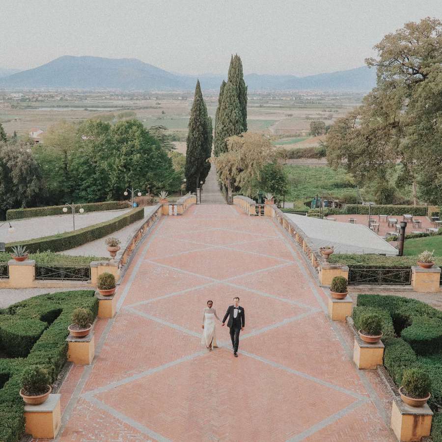 Portrait of Bride and Groom Holding Hands Walking on Patio at Italian Wedding Venue