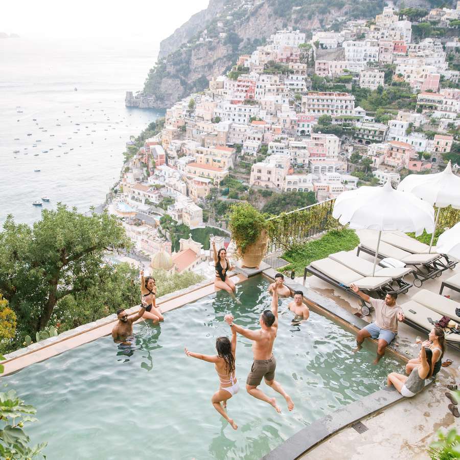 Bride and groom jumping into a pool with their friends on the Amalfi Coast