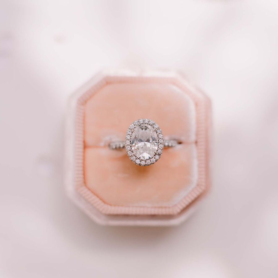 Oval diamond halo engagement ring displayed in a pink box